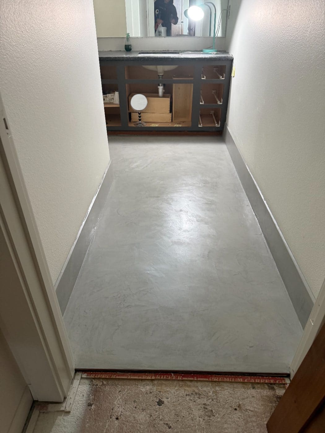Same powder room floor finished in microcement, tile removed by coating over it